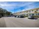 Low angle exterior view of multi-unit dwelling with lush trees and front parking at 500 Glennes Ln # 202, Dunedin, FL 34698
