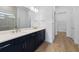 Modern bathroom features a double sink vanity with blue cabinets and a door to the walk-in closet at 6072 Silver Grass Ct, Nokomis, FL 34275