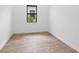 Bedroom showcasing modern wood-look flooring and a bright window at 6072 Silver Grass Ct, Nokomis, FL 34275