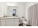 Well-lit bathroom features a sink with granite countertop, white cabinets, decorative mirror and shower with curtain at 6235 Bucket Ct, Gibsonton, FL 33534
