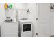 Well-lit laundry area with modern washer and dryer, plus a shelf for supplies at 6235 Bucket Ct, Gibsonton, FL 33534