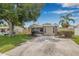 Charming single-story home with a well-manicured lawn, mature trees, and a welcoming light blue front door at 6944 80Th N Ave, Pinellas Park, FL 33781