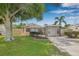 Charming single-story home with a well-manicured lawn, mature trees, and a welcoming light blue front door at 6944 80Th N Ave, Pinellas Park, FL 33781