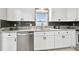 Bright kitchen features white cabinets, stainless steel appliances, and stone countertops with backsplash at 701 Poinsettia Rd # 322, Belleair, FL 33756
