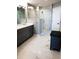 This updated bathroom features dual sinks, updated fixtures, a glass-enclosed shower, and modern finishes at 706 Bayway Blvd # 502, Clearwater Beach, FL 33767