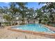 Well-maintained community pool with an expansive deck, lush trees, and covered cabana area at 720 Lyndhurst St # 1101, Dunedin, FL 34698