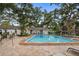 Inviting community swimming pool area with lounge chairs and seating under mature shade trees at 720 Lyndhurst St # 1101, Dunedin, FL 34698