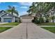 Well-maintained single-story home featuring a large driveway, mature trees, and lush landscaping at 7603 Wood Violet Dr, Gibsonton, FL 33534