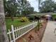 A lovely backyard with a white picket fence, lush plants, trees, and a view of the in-ground pool at 820 Crenshaw Lake Rd, Lutz, FL 33548