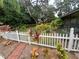 A charming backyard showcasing landscaping and a white picket fence surrounding the property at 820 Crenshaw Lake Rd, Lutz, FL 33548