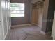 An open bedroom space with neutral walls, an open closet, a bright window, and vinyl floors at 820 Crenshaw Lake Rd, Lutz, FL 33548