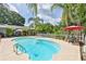 Inviting backyard pool with mature landscaping and a white picket fence creating a private oasis at 820 Crenshaw Lake Rd, Lutz, FL 33548
