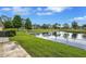 Scenic pond view lined with lush green grass and a walking path in a well-maintained community at 900 Maclaren N Dr # D, Palm Harbor, FL 34684