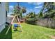 Fenced in backyard with lush green lawn, swing, slide, and a shaded seating area at 910 E Crenshaw St, Tampa, FL 33604
