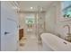 This bathroom has a dual vanity with wooden cabinets, a soaking tub, and a glass-enclosed shower at 910 E Crenshaw St, Tampa, FL 33604