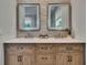 This bathroom includes a dual sink vanity with wooden cabinets and two mirrors with stone backdrops at 910 E Crenshaw St, Tampa, FL 33604