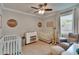 Bright bedroom featuring a ceiling fan, two cribs, and neutral tones throughout at 910 E Crenshaw St, Tampa, FL 33604