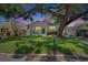 Charming home at dusk, featuring a well-manicured lawn, mature tree, and a welcoming front porch at 910 E Crenshaw St, Tampa, FL 33604
