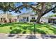 Quaint home with a lush green lawn, shaded by a large tree, and featuring a charming front porch at 910 E Crenshaw St, Tampa, FL 33604