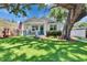 Charming home with a well-manicured lawn and mature shade trees, complemented by a welcoming blue front door at 910 E Crenshaw St, Tampa, FL 33604