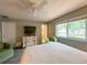 Bedroom with hardwood flooring, a ceiling fan, a window, a TV, and green walls providing a serene retreat at 9951 121St St, Seminole, FL 33772