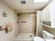 Tiled shower with rainfall showerhead and separate handheld shower, grab bar, and storage at 9951 121St St, Seminole, FL 33772