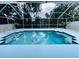 Sparkling blue swimming pool with a screened enclosure, surrounded by a concrete deck and lush greenery at 10444 Fordham St, Spring Hill, FL 34608