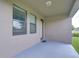 Back patio with brown trimmed windows and door with grey floor and green yard at 11011 Little Blue Heron Dr, Riverview, FL 33579