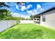 Spacious backyard with healthy green lawn, mature trees, and a white picket fence at 11011 Little Blue Heron Dr, Riverview, FL 33579