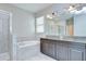 Bright bathroom featuring double vanity, soaking tub, and glass-enclosed shower at 11011 Little Blue Heron Dr, Riverview, FL 33579