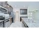 Modern kitchen featuring stainless steel appliances, dark cabinetry, and granite countertops at 11011 Little Blue Heron Dr, Riverview, FL 33579