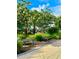 Two park benches are situated near flowering trees and a walking path at 11011 Little Blue Heron Dr, Riverview, FL 33579