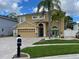 Two-story tan home with an attached two-car garage, paver driveway, and lush landscaping at 1205 Sweet Gum Dr, Brandon, FL 33511