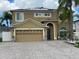 Two-story home with a two-car garage, tan stucco, blue door and a paver driveway framed by palm trees at 1205 Sweet Gum Dr, Brandon, FL 33511