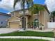 Tan home with a front yard featuring mature landscaping and a paver driveway leading to an attached two-car garage at 1205 Sweet Gum Dr, Brandon, FL 33511