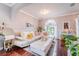 Elegant living room with wood floors, a white leather sofa, colorful throw pillows and an arched window with sheer curtains at 1205 Sweet Gum Dr, Brandon, FL 33511