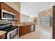 A kitchen offering stainless appliances, wood cabinets, tile backsplash, and an open view into the living room at 12405 Pathway Ct, Riverview, FL 33569