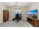 Well-lit home office with a large TV, bookshelf, a modern chandelier, and comfortable office furniture at 12607 Pensacola Ct, Riverview, FL 33579