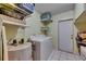 Laundry room with white tile floors, shelving, utility sink, hot water tank, and washer and dryer at 15820 Sapwood St, Tampa, FL 33624