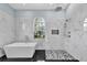 Elegant bathroom with marble walls, a large stand alone tub, and a shower with black and white accents at 1716 Bermuda Ct, Safety Harbor, FL 34695