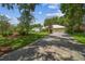 Home exterior featuring a long driveway, lush lawn, beautiful trees and landscaping at 17906 Loretta Ln, Lutz, FL 33548