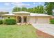Beautiful tan single-story home with a manicured lawn, clean landscaping, and a white roof at 17906 Loretta Ln, Lutz, FL 33548