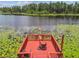 Aerial close-up of a red deck overlooking the lake with water lilies and an umbrella with two chairs at 17906 Loretta Ln, Lutz, FL 33548