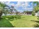 Expansive, fenced backyard with lush green grass and a covered patio perfect for entertaining or relaxation at 2025 Jefferson Ave, Dunedin, FL 34698