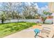 Spacious fenced backyard features a grassy area, mature trees and BBQ grill at 2025 Jefferson Ave, Dunedin, FL 34698