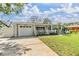 Inviting home with a well-kept lawn, a paved driveway leading to an attached garage, and a charming white picket fence at 2025 Jefferson Ave, Dunedin, FL 34698