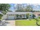 Lovely home featuring a one car garage, cozy front porch, and a beautifully maintained yard with mature landscaping at 2025 Jefferson Ave, Dunedin, FL 34698