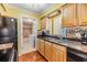 Kitchen with wood cabinets, granite counters, colorful backsplash, leading into adjacent bathroom at 2025 Jefferson Ave, Dunedin, FL 34698