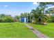 Spacious backyard with well-maintained lawn, vibrant foliage, brick path, and a shed at 217 W Powhatan Ave, Tampa, FL 33604