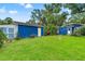 Lush backyard featuring a well-kept lawn, mature trees, and a blue shed with yellow door at 217 W Powhatan Ave, Tampa, FL 33604
